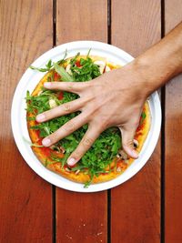 Cropped hand on pizza over table