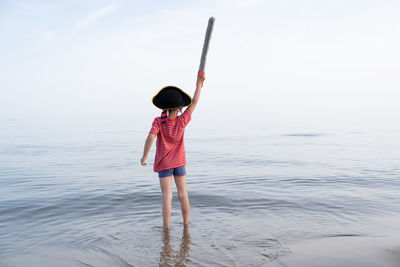 Rear view of woman standing on beach against sky