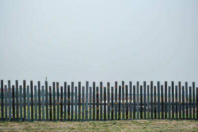 Wooden fence on field against clear sky