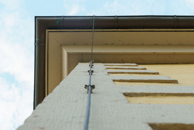 Low angle view of cross on building against sky