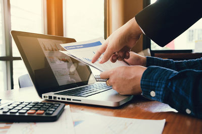 Midsection of man using laptop on table