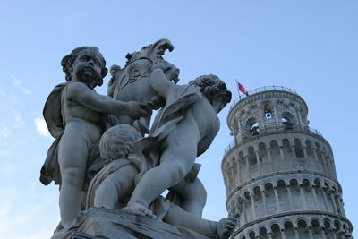 Low angle view of statue against historic building - leaning tower of pisa