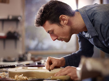 Side view of man making guitar