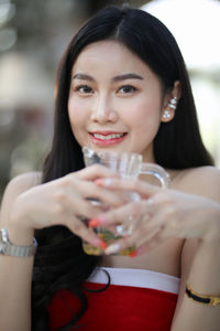 Portrait of smiling young woman holding drink