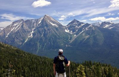 Rear view of man standing on mountain against sky