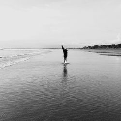 Man walking on beach against sky