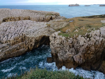 Scenic view of rocks on sea shore against sky