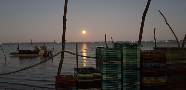 Sailboats moored at harbor against sky during sunset