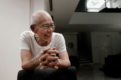 Smiling senior man looking away while sitting at home