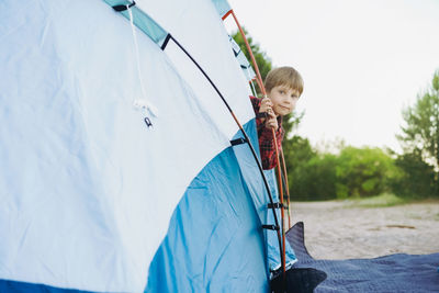 Cute little caucasian boy looking out from touristic tent. family camping concept