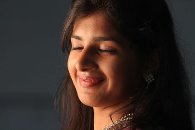 Portrait of smiling young woman against black background