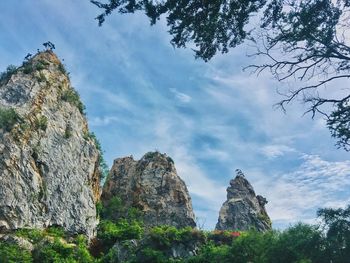 Low angle view of rocks and trees against sky