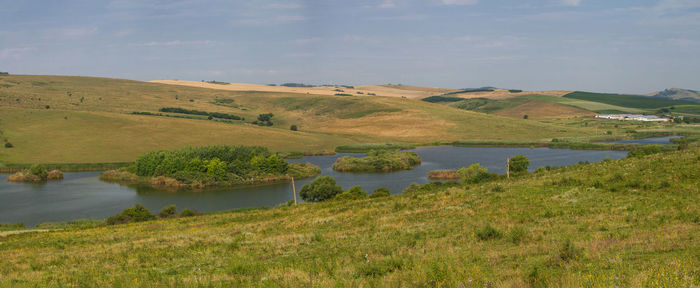 Scenic view of river amidst field against sky