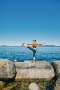 Young woman practicing yoga on lake tahoe in northern california.