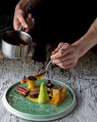 Close-up of person preparing food in plate