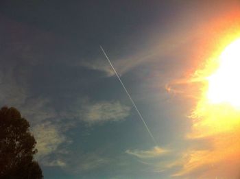 Low angle view of sun shining through clouds