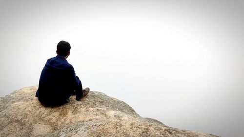 Man sitting on an edge of rock and enjoying the view