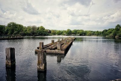 Wooden posts in lake against sky