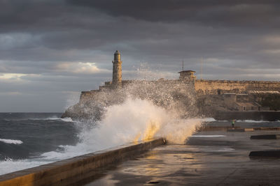 Sea waves splashing on shore against sky