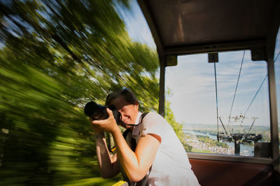 Side view of woman photographing in overhead cable car