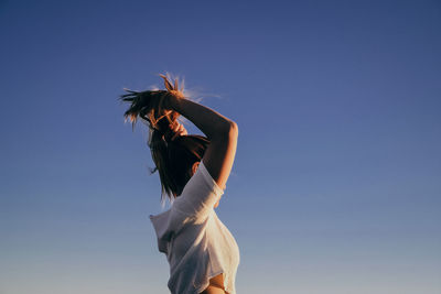 Woman with palm tree against clear blue sky