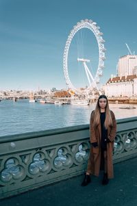 Portrait of woman with ferris wheel against sky