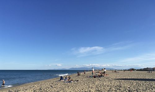 People on beach against blue sky