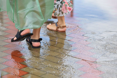 Low section of women standing on wet street