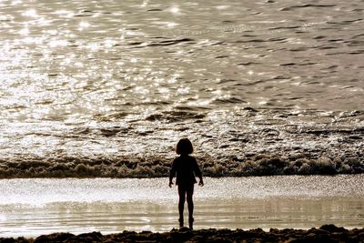 Rear view of silhouette man standing at beach