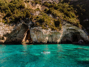 Woman paddleboarding on sea against cliff