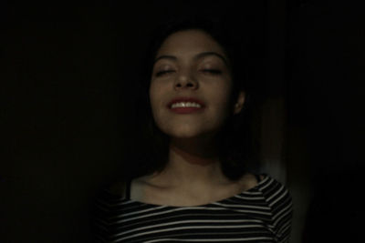 Portrait of young woman against black background