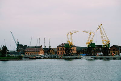 Cranes by river against sky