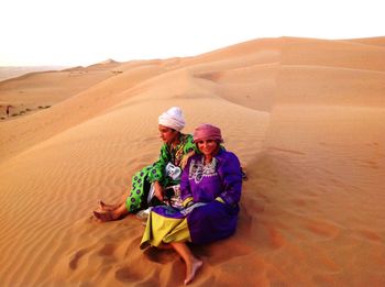 Women sitting on sand dune in desert