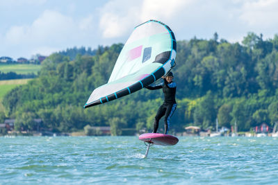 Woman wing foiling on lake wallersee, salzburg, austria.