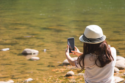 Rear view of woman photographing with mobile phone
