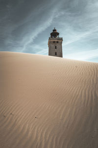 Lighthouse on beach against sky