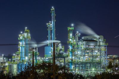 Illuminated factory against sky at night