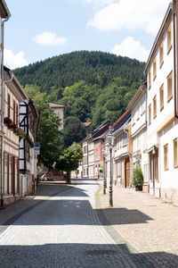 Road amidst buildings in town against sky