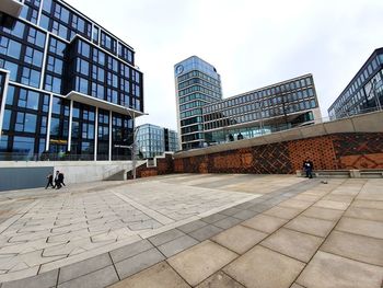 People in modern building against sky in city