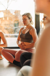 Woman with hands on stomach sitting cross-legged at retreat center