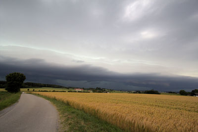 Scenic view of road amidst field against sky