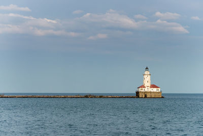 Lighthouse by sea against sky