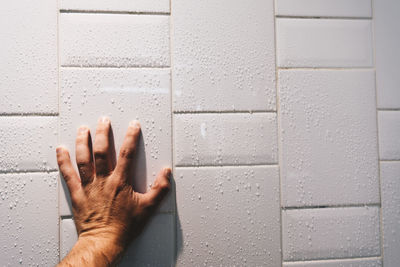 Close-up of human hand against wall