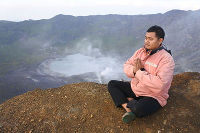 Young man sitting on rock