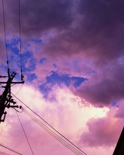 Low angle view of electricity pylon against cloudy sky