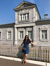 Full length portrait of woman standing against building