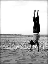 Person doing handstand on sandy beach