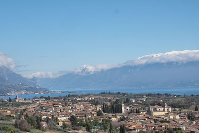 Aerial view of houses and mountains against blue sky