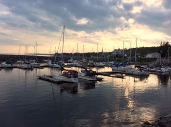 Boats moored in harbor at sunset