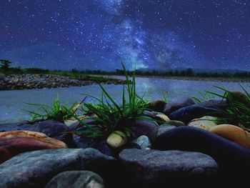Rocks by sea against sky at night